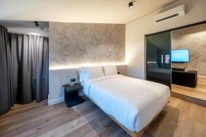 ein Schlafzimmer mit einem großen weißen Bett und einem TV in der Unterkunft Palazzo Licinio in Venafro
