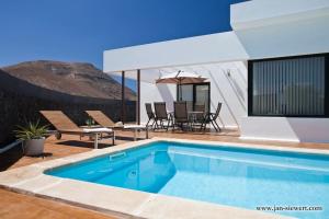 a swimming pool with a table and chairs next to a house at Villa Andy Lanzarote in Yaiza