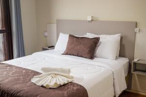 um quarto com uma cama grande com lençóis brancos e almofadas em Pousada Paraíso em Cambará