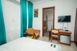 a bedroom with a bed and a desk and a television at Beauty Hotel in Accra