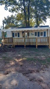 a house with a porch and a wooden fence at Mobil-Home The Duck in Saint-Paul-lès-Dax