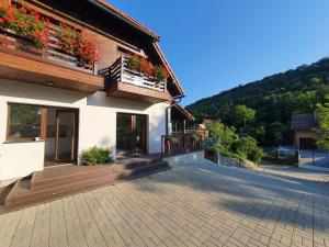 a house with a balcony with flowers on it at Double room in Pensiunea Nossa Panzió in Corunca