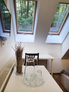a table with glasses and a vase on it with windows at Double room in Pensiunea Nossa Panzió in Corunca +11 photos