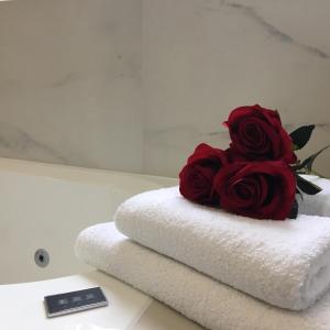een boeket rode rozen op een stapel handdoeken bij Family & Business Sauna Apartments No2 Leśny nad Zalewem Cedzyna - 2 Bedroom with Private Sauna, Bath with Hydromassage, Terrace, Parking, Catering Options in Kielce