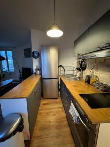 una cucina con frigorifero in acciaio inossidabile e piano di lavoro in legno di Cosy appartement lumineux ad Arcueil