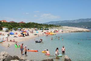 a group of people on a beach in the water at Apartments Vrban in Šilo