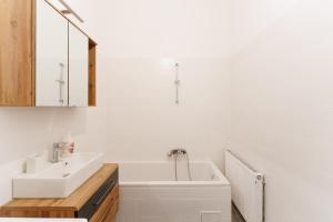 y baño blanco con lavabo y bañera. en Central, modern, big apartment, en Viena