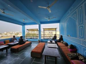 a group of people sitting on benches in a room with blue walls at Madpackers Udaipur in Udaipur