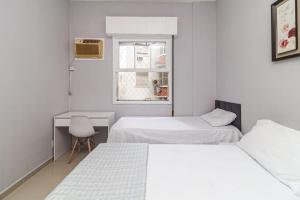 Pokój z 2 łóżkami, biurkiem i oknem w obiekcie Apartamento a 140 metros da Praia de Santos w mieście Santos