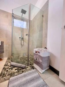 een badkamer met een douche en een glazen deur bij Kozy Korner Apartment in Baie du Tombeau