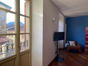 a room with a window and a chair and a television at La Porta Azzurra - Casa Vacanze in Como