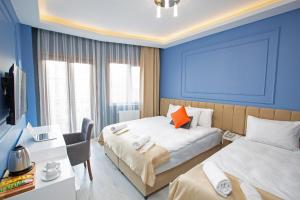 a bedroom with two beds and a desk and a tv at Taksim Leon's Hotel in Istanbul