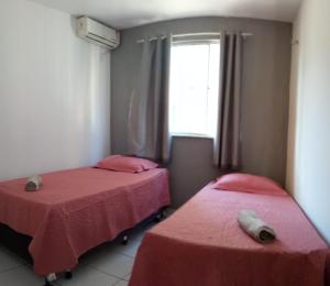 two beds in a room with red sheets and a window at A FELICIDADE MORA AQUI in São Luís