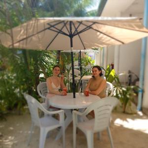 two women sitting at a table under an umbrella at Sunrise Inn in Thoddoo