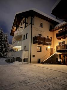 un gran edificio en la nieve por la noche en Apart Berghof, en Fiss