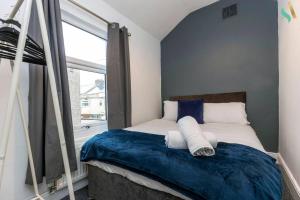een slaapkamer met een bed met blauwe lakens en een raam bij Everett House in Hartlepool