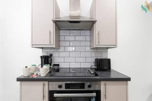 een keuken met witte kasten en een fornuis met oven bij Everett House in Hartlepool
