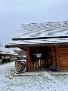 a log cabin with a table and chairs in the snow at Cabana Huta Slavia in Şinteu