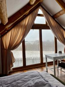 a bedroom with a large window with a bed and a table at Cabana Huta Slavia in Şinteu