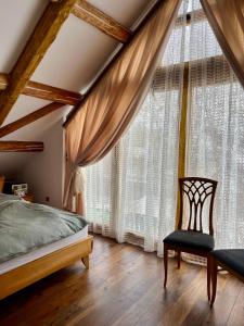 a bedroom with a bed and a chair and large windows at Cabana Huta Slavia in Şinteu