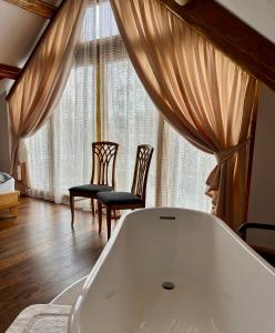 a bath tub in a room with two chairs at Cabana Huta Slavia in Şinteu