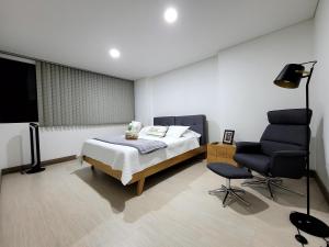 - une chambre avec un lit et une chaise dans l'établissement New Luxury 3 Bedroom Apartment in Great Area., à Medellín