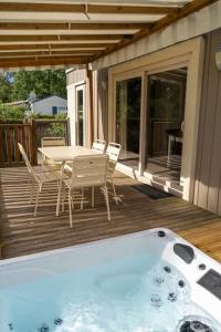 d'une terrasse avec une table, des chaises et une baignoire. dans l'établissement Camping du Château Vert, à Hondainville