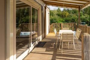 une terrasse en bois avec une table et des chaises. dans l'établissement Camping du Château Vert, à Hondainville