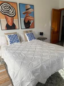 Timijiraque的住宿－APARTAMENTO ROSALIA，卧室内的一张白色大床,配有绘画作品