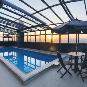 eine Terrasse mit einem Tisch und einem Sonnenschirm neben einem Pool in der Unterkunft Aquarius Flat Studio 509 in Santa Cruz do Sul