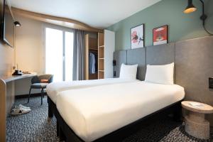 パリにあるイビス パリ ガール ドゥ リヨン ルイイの大きなベッドとデスクが備わるホテルルームです。