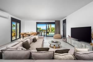 un soggiorno con un grande divano e una TV a schermo piatto di Penélope Beachfront Villa a Kremasti