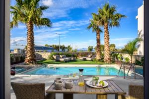 einen Tisch mit Speisen und Getränken auf einer Terrasse mit Palmen in der Unterkunft Penélope Beachfront Villa in Kremasti