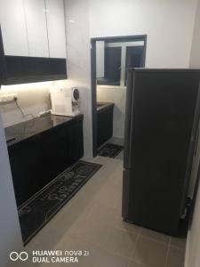 eine Küche mit einem schwarzen Kühlschrank im Zimmer in der Unterkunft Simfoni 2 in Semenyih