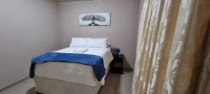 Sapphire Lodge في Siteki: غرفة نوم صغيرة مع سرير وبطانية زرقاء