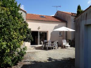 a patio with a table and chairs and an umbrella at Villa Vanille in Châtelaillon-Plage