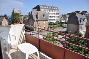einen Balkon mit einem weißen Tisch, Stühlen und Gebäuden in der Unterkunft Bel appartement 2 chambres au centre-ville de PERROS-GUIREC - Ref 926 in Perros-Guirec