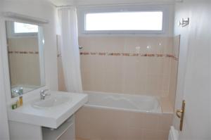 ein Bad mit einem Waschbecken, einer Badewanne und einem Fenster in der Unterkunft Bel appartement 2 chambres au centre-ville de PERROS-GUIREC - Ref 926 in Perros-Guirec