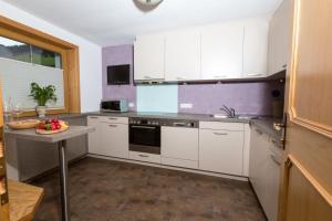 a kitchen with white cabinets and a table in it at Alpinhome in Tux +24 photos