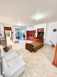 a living room with a white couch and a television at Casa con piscina y salida a la playa in Playas