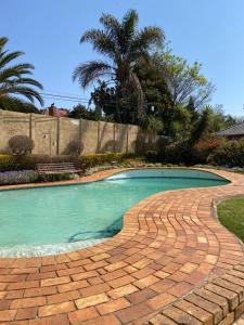 a brick walkway around a swimming pool in a yard at Always Here for you in Krugersdorp