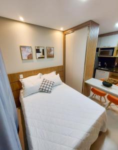 a bedroom with a white bed and a kitchen at APARTAMENTO FLAT STUDIO WEST FIT 711 a in Mossoró