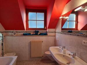 a bathroom with red walls and a sink and a toilet at Penthouse&Wellness L'Abete in Gargazzone +23 photos