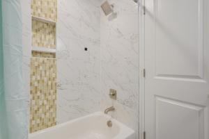 a white bathroom with a tub and a shower at North Charleston Escape about 15 Mi to Dtwn Charleston in Charleston +19 photos