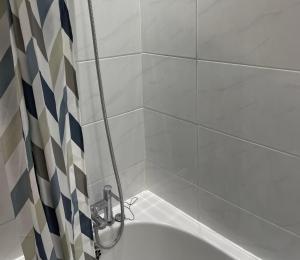 a bathroom with a bath tub with a shower at Walk to Lcy Airport Excel Dlr 1Br Flat in London