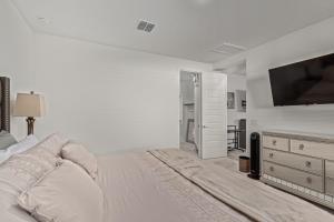 a white bedroom with a bed and a flat screen tv at AT YOUR SERVICE - Modern Amenities, Urban Location, Sophisticated Style in Phoenix