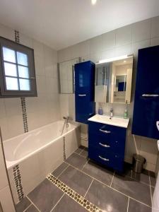 La salle de bains est pourvue d'une baignoire, d'un lavabo et de placards bleus. dans l'établissement Maison équipée, wifi, TV, jardin, à Saint-Martin-de-Mailloc