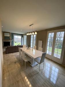 une salle à manger avec une table et des chaises blanches dans l'établissement Maison équipée, wifi, TV, jardin, à Saint-Martin-de-Mailloc