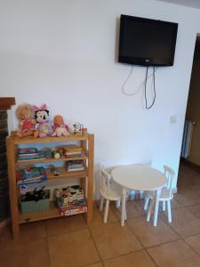 a table and a shelf with stuffed animals and a tv at Mora de Nuei in Aínsa