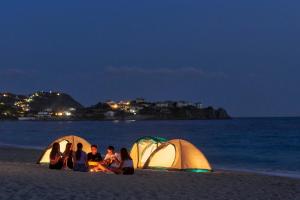 a group of people sitting around a campfire on the beach at Calaserena Resort in Geremèas